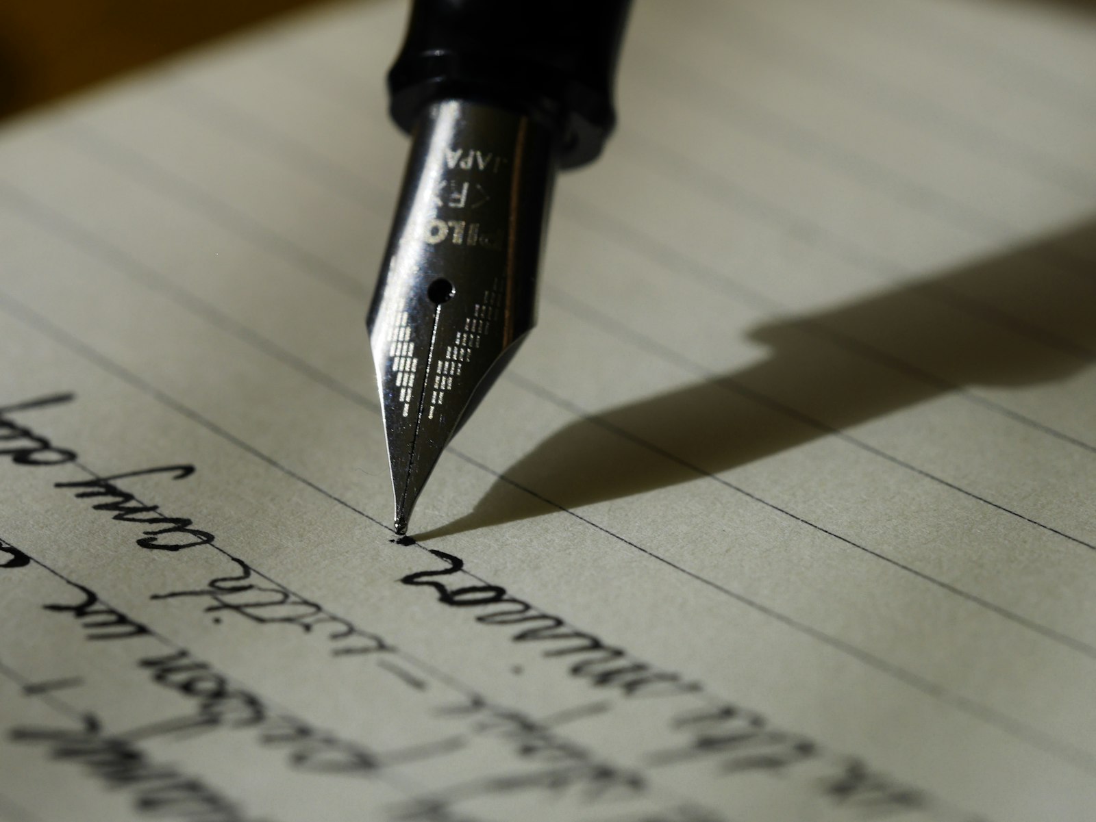 Hands writing in a notebook beside a laptop